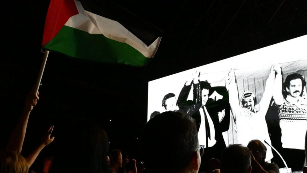 Στην οθόνη, κατά τη διάρκεια της συναυλίας από το ΚΚΕ για τα 100 χρόνια του Μίκη, προβάλλεται φωτογραφία του με τον Γιάσερ Αραφάτ και τον Γιώργο Παπαπέτρου στη Βηρυτό
